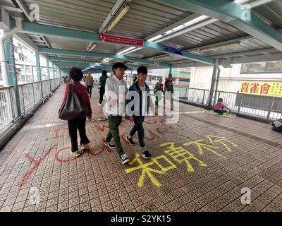 Les piétons circulant sur des slogans graffiti peint par manifestants exiger leurs droits à Hong Kong. Banque D'Images