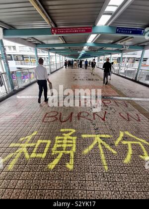 Les piétons circulant sur des slogans graffiti peint par manifestants exiger leurs droits à Hong Kong. Banque D'Images