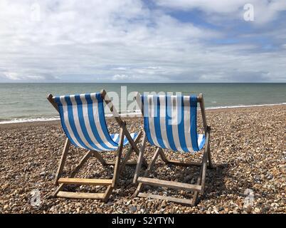 Deux chaises longues à rayures bleues et blanches qui font face à la mer, sur une plage de galets vide à Brighton, East Sussex, Angleterre, Royaume-Uni Banque D'Images