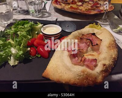 Pizza calzone "fermé" avec salade.Soft et chorizo,red chili,poivrons,tomates,mozzarella,rocket,pesto et fromage italien. Banque D'Images