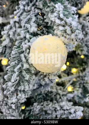 Brillant doucement Christmas Tree ornament hanging on a snowy pine tree Banque D'Images