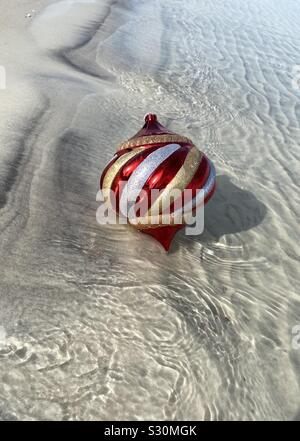 Bal de Noël coloré flottant dans l'eau sur plage de sable blanc Banque D'Images