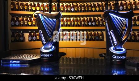 Pompes à bière Guinness dans un bar avec des bouteilles de Guinness sur les étagères derrière. Guinness Storehouse à Dublin en Irlande Banque D'Images
