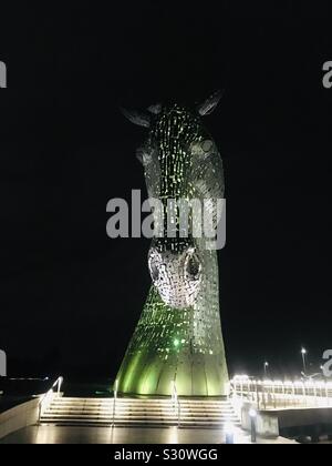 L'un des Kelpies de nuit, illuminé en vert. A 30m de haut, tête de cheval géant Sculpture du Forth et Clyde Canal dans le parc de l'hélice, Falkirk, Ecosse par Andy Scott Banque D'Images