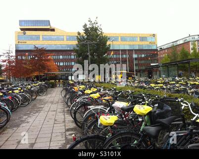 Des milliers de vélos garés et couvert avec pluie couvre selle (promotion) de marque stationné près d'Uppsala city gare parking qui subit une construcion d'un immense parking à l'intérieur du site. La Suède Banque D'Images