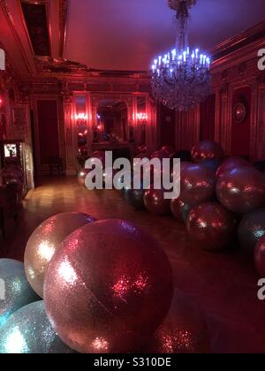 Boules de Noël Décoration scintillants géant organisé à travers le plancher d'un salon dans un manoir anglais à la française dans la nuit éclairée par des chandeliers. Banque D'Images