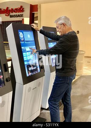 Man l'achat d'un billet de cinéma à un guichet automatique de la machine à un cinéma. Banque D'Images