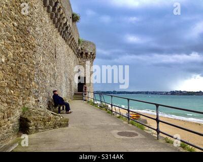 Français assis et profitant de la vue sur l'océan depuis un banc de fort Royal, rebaptisé fort National à Saint-Malo, France. Banque D'Images