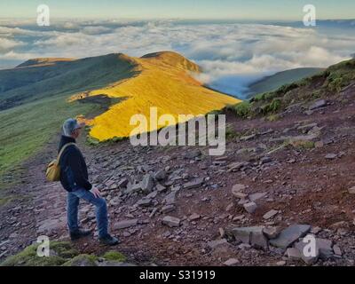 L'homme regardant vers le bas sur le Llwch Cefn MCG à l'approche du sommet de Pen Y Fan, Brecon Beacons, Galles, décembre. Banque D'Images