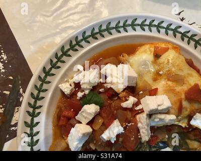 Le petit déjeuner moyen-orientale plat de Shakshouka faite par le braconnage des oeufs dans les tomates, oignons, poivrons, l'ail et les épices et garni de fromage feta et à la coriandre (cilantro). Banque D'Images