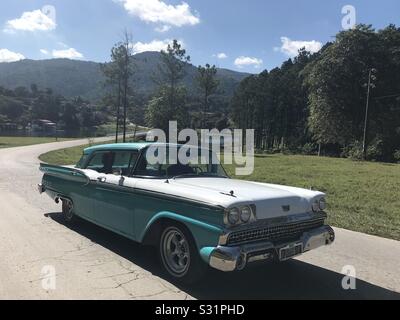 Voiture cubaine classique conduire sur une route sinueuse dans la forêt de Las Terrazas Banque D'Images