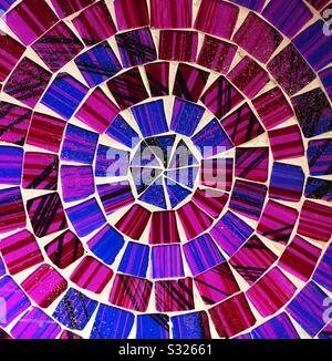 Mosaïques colorées et éclatantes dans un motif circulaire avec des purples et des bleus dans une image d'arrière-plan en céramique colorée Banque D'Images