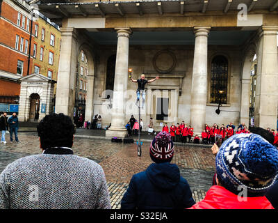 Les touristes regardent un artiste de rue sur un Unicycle en dehors de l’église St Paul, Covent Garden, Londres, Angleterre Banque D'Images