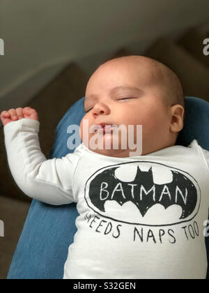Un bébé de 8 semaines qui nait sur ses pères se laissait vêtu de Batman. Banque D'Images
