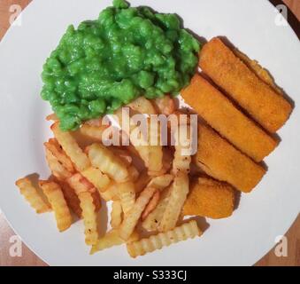 Un repas complet de doigts de poisson, de petits pois et de chips, sur une plaque blanche, vue de dessus. Banque D'Images