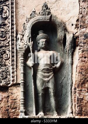 Sculpture d'un Dieu gardien hindou tenant un trident, temple de Preah Ko, Roluos, Cambodge Banque D'Images