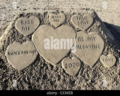 Un château de sable sur la plage a des coeurs de Saint-Valentin avec des adorations mignonnes sur l'amour. Banque D'Images