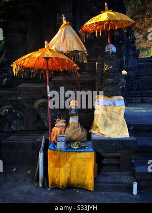 Statues décorées et canang sari (offrandes quotidiennes) à l'entrée de Pura Candidasa, Bali, Indonésie Banque D'Images