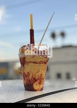 Une boisson traditionnelle gelée de mangonada mexicaine, composée de sorbet de mangue, de morceaux de mangue, de chamoy, de chaux, de poudre de tajin et de bonbons de tamarin, est présentée dans une tasse en plastique transparent. Banque D'Images