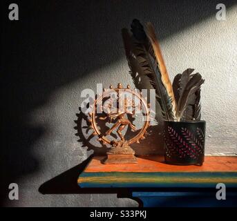 Une étagère colorée tenant une danse en bronze Shiva statuette et quelques oiseaux plumes, ombre et lumière, nouvel âge spirituel avec espace de copie Banque D'Images