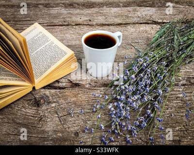Tasse de café, un livre et des fleurs de lavande sur une table rustique en bois Banque D'Images