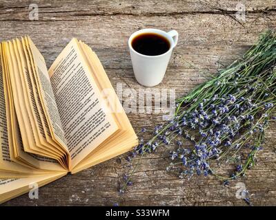 Tasse de café, un livre et des fleurs de lavande sur une table rustique en bois Banque D'Images