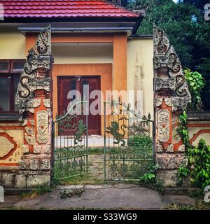 L'entrée à une maison balinaise moderne, composée d'un bentar traditionnel de di, ou passerelle divisée, et portes en fer avec des motifs de lion, Candidasa, Bali, Indonésie Banque D'Images