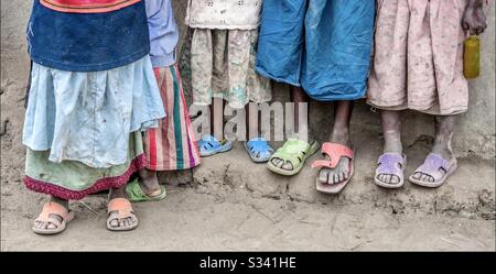 Gros plan de robes et de chaussures très colorées de la taille vers le bas sur un groupe de filles africaines de la tribu des Maasai en Tanzanie, Afrique. Banque D'Images