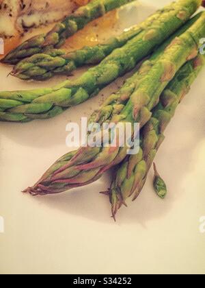 Des asperges fraîchement cuites épient sur une assiette blanche pour le dîner Banque D'Images