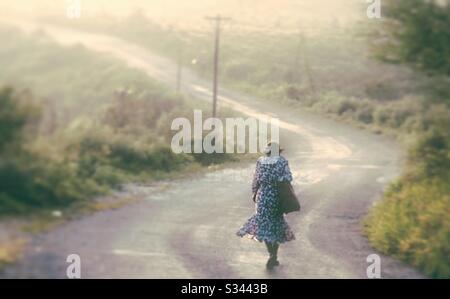 Une femme âgée marchant le long d'une route de campagne en Jamaïque Banque D'Images