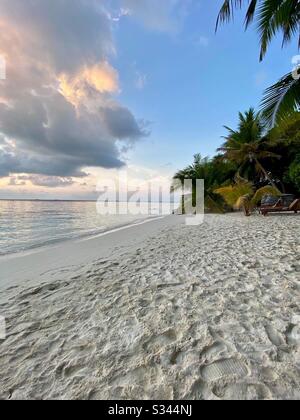 Empreintes sur une plage de sable tropical vide aux Maldives au crépuscule Banque D'Images