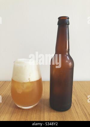 Verre de Tepache mousse à côté de la bouteille brune sur la table Banque D'Images