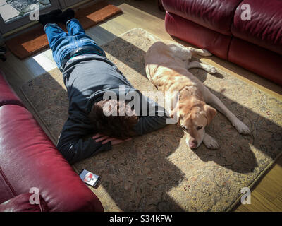 Amitié. Un garçon et son chien endorment sur le sol. Banque D'Images
