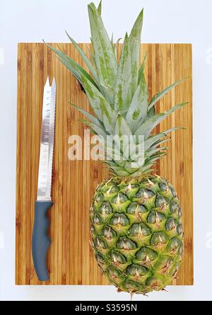 Préparer un ananas entier dans la cuisine. Préparation de fruits frais et mûrs. Ingrédients pour la salsa d'ananas maison. Sur une planche à découper en bois avec couteau Banque D'Images