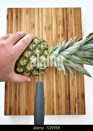 Préparer un ananas entier dans la cuisine. Préparation de fruits frais et mûrs. Ingrédients pour la salsa d'ananas maison. Sur une planche à découper en bois avec couteau Banque D'Images