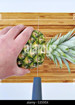 Préparer un ananas entier dans la cuisine. Préparation de fruits frais et mûrs. Ingrédients pour la salsa d'ananas maison. Sur une planche à découper en bois avec couteau Banque D'Images