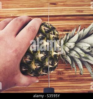 Préparer un ananas entier dans la cuisine. Préparation de fruits frais et mûrs. Ingrédients pour la salsa d'ananas maison. Sur une planche à découper en bois avec couteau Banque D'Images