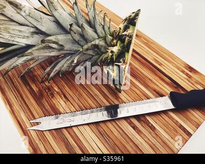 Préparer un ananas entier dans la cuisine. Préparation de fruits frais et mûrs. Ingrédients pour la salsa d'ananas maison. Sur une planche à découper en bois avec couteau Banque D'Images