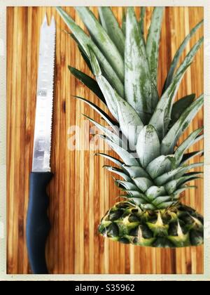 Préparer un ananas entier dans la cuisine. Préparation de fruits frais et mûrs. Ingrédients pour la salsa d'ananas maison. Sur une planche à découper en bois avec couteau Banque D'Images