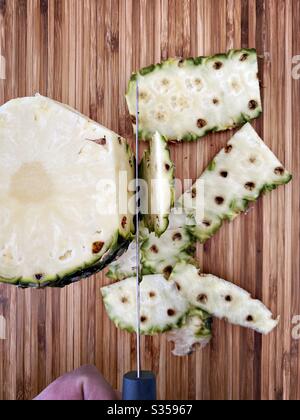 Préparer un ananas entier dans la cuisine. Préparation de fruits frais et mûrs. Ingrédients pour la salsa d'ananas maison. Peau de peeling sur une planche à découper en bois avec couteau Banque D'Images