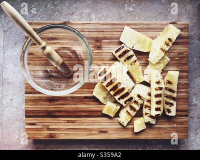 Préparation du dîner dans la cuisine. Préparation de nourriture fraîche. Ingrédients pour la salsa d'ananas maison. Tranches de bois grillé sur une planche à découper en bois et une marinade au miel Banque D'Images