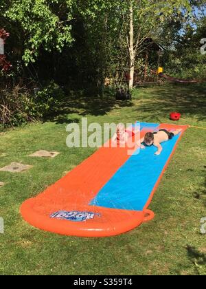 Deux garçons jouant sur un slip et un slide. Banque D'Images
