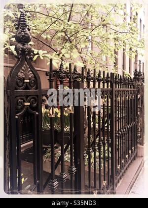 Clôture en fer forgé et arbres en fleurs à l'extérieur des pierres bronnières historiques dans le quartier de Murray Hill à Manhattan, au printemps après-midi Banque D'Images