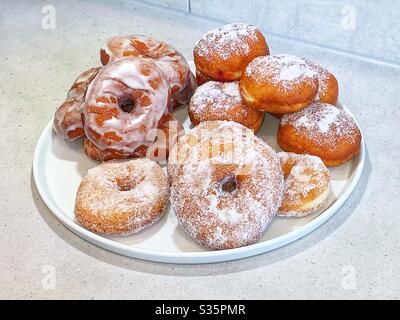 Plaque blanche de beignets faits maison. Beignets à anneaux et beignets remplis de confiture. Banque D'Images