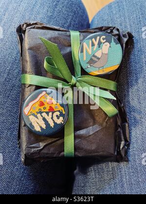 Petit cadeau avec boutons NYC sur les genoux d’une femme Banque D'Images