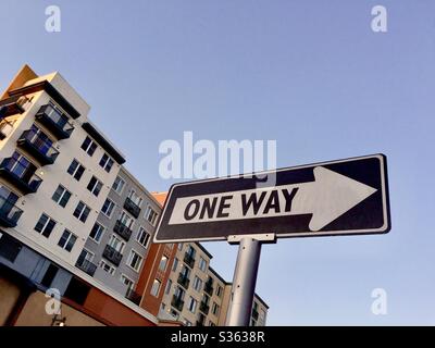 Panneau de rue flèche à sens unique avec appartements modernes pastel de quatre étages derrière. Bay Street, Emeryville, Californie. Banque D'Images