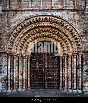 Une porte d'église gothique et ornée avec arches et piliers en pierre sculptés et complexes avec une porte en bois solide et lourde Banque D'Images