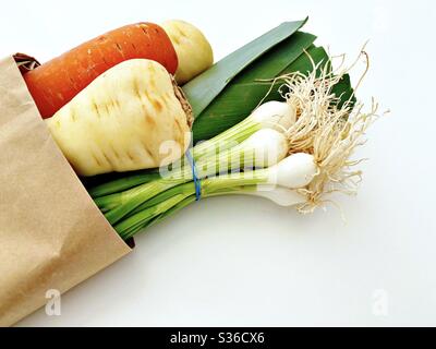 Les produits frais du marché agricole sont produits dans un sac de papier marron isolé sur fond blanc. Poireaux, ciboules, carottes, panais. Légumes biologiques. Banque D'Images