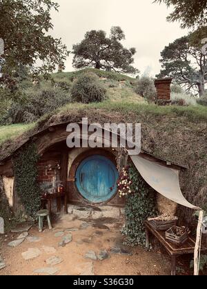 Hobbitebourg. Bucolique lieu en Nouvelle-Zélande où vivent les hobbits de la Terre du milieu. Ensemble de films Lord of the Rings. Porte ronde bleue entourée d'arbres Banque D'Images