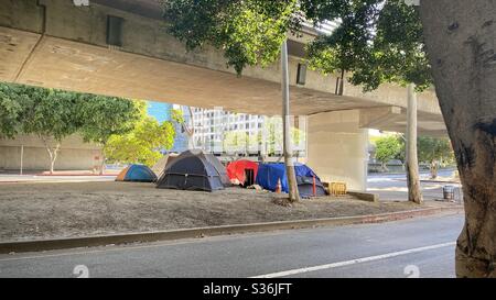 LOS ANGELES, CA, MAI 2020 : campement pour sans-abri à grande vue composé de plusieurs tentes, près des immeubles de bureaux, des appartements et des hôtels, sous un pont supérieur dans le centre-ville. Banque D'Images